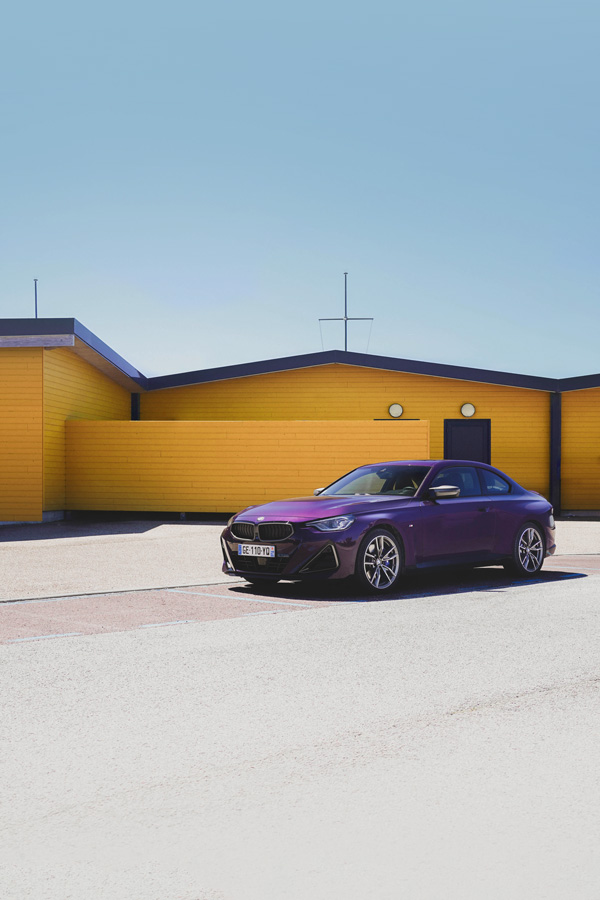 BMW M240i violette devant une architecture jaune