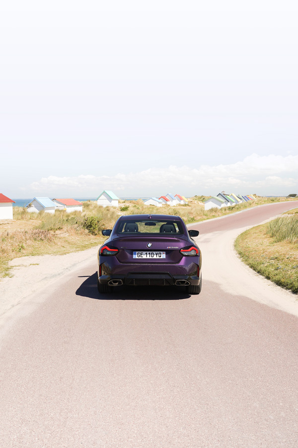 Shooting photo d'une BMW violette devant des cabines colorées